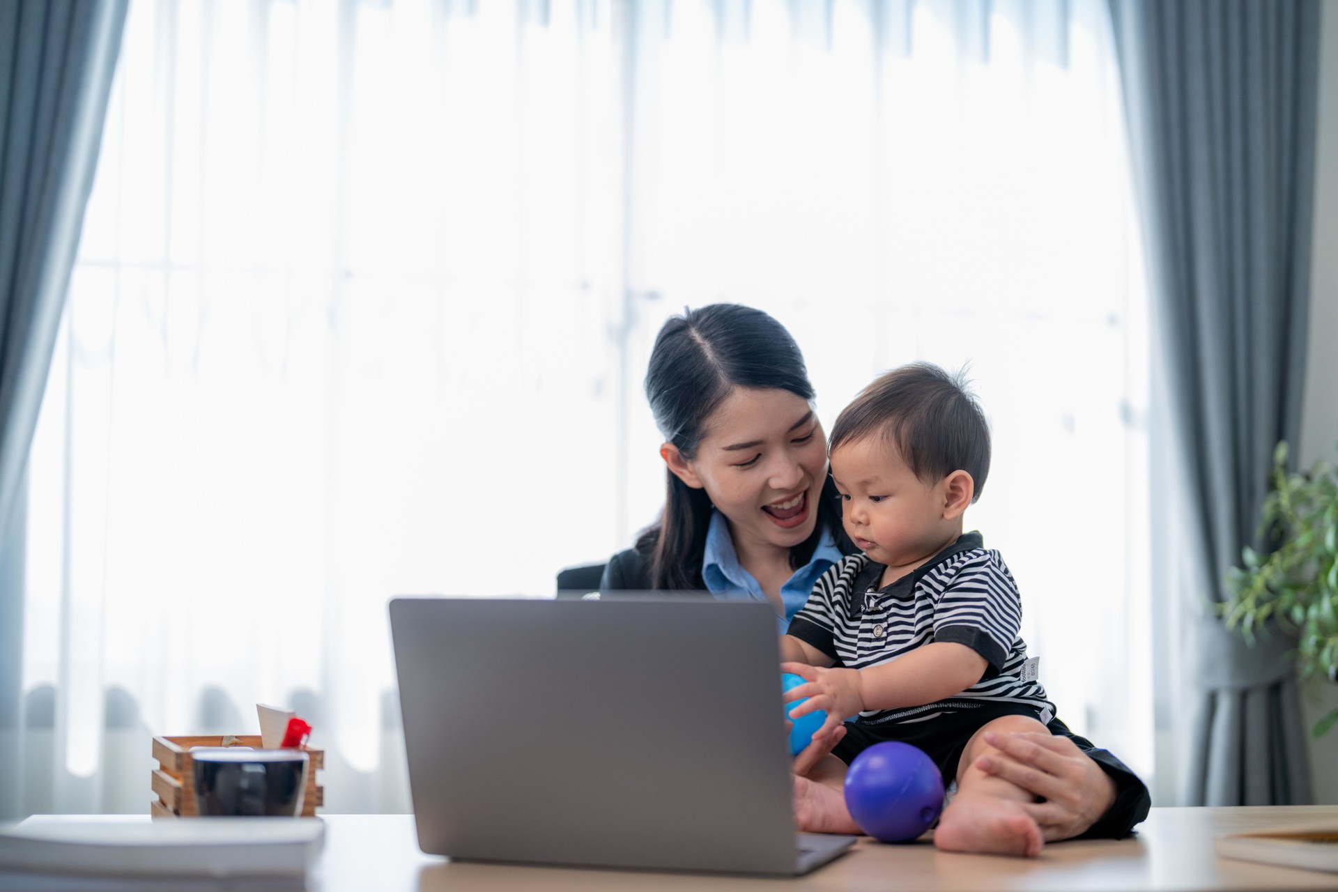 Working mother engages with her toddler during a home office session in bright, cozy environment